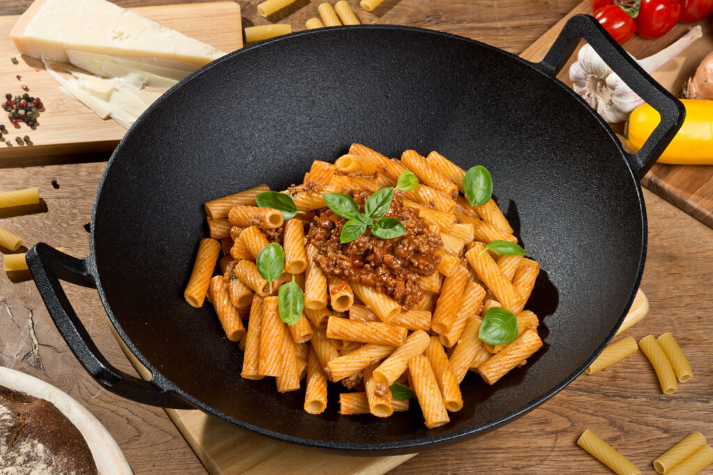 gusseiserner Wok mit Pasta auf Tisch